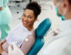 Woman smiling up at dentist in dental chair with bright white smile