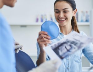 Woman smiling into mirror at dentist