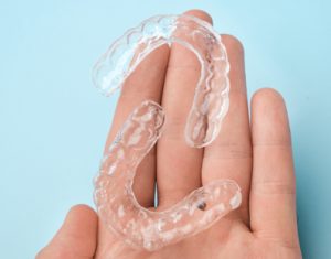 Hand holding out 2 clear aligners