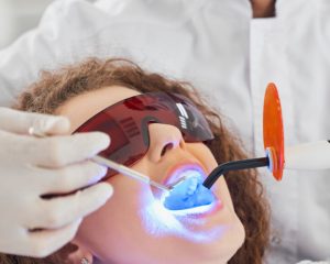Woman having dentist look inside mouth with goggles on