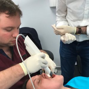 Geraint using the intraoral scanner on a patient during practice, with anothe dental nurse standing by for assistance
