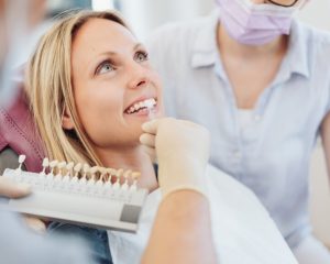 Woman smiling whilst dentist holds up colour chart against teeth