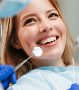 Woman smiling up at dentist with dental tool in front of her