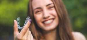 Blurred image of woman holding clear aligner in focus